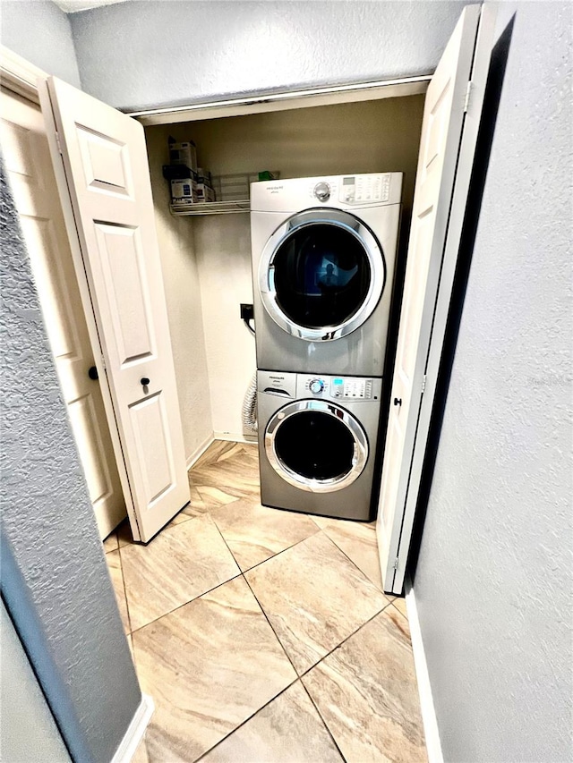 laundry room featuring light tile patterned floors and stacked washer and dryer