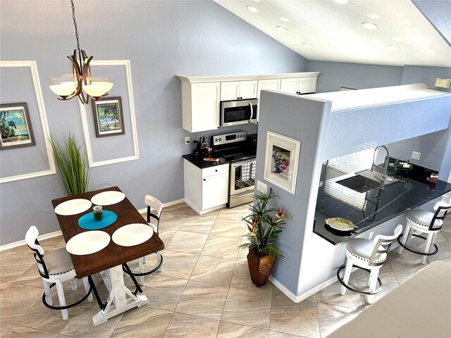 kitchen featuring lofted ceiling, an inviting chandelier, white cabinets, hanging light fixtures, and appliances with stainless steel finishes