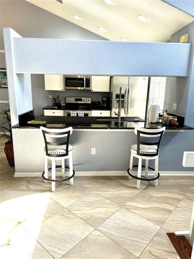 kitchen with white cabinets, vaulted ceiling, and appliances with stainless steel finishes