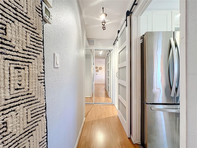 hall featuring a barn door and light hardwood / wood-style floors