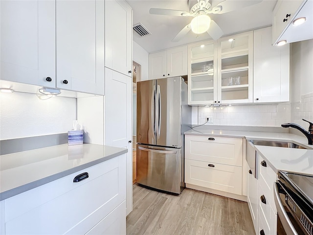 kitchen featuring white cabinets, light hardwood / wood-style flooring, tasteful backsplash, and stainless steel refrigerator