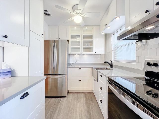 kitchen with electric range oven, white cabinetry, tasteful backsplash, light hardwood / wood-style floors, and stainless steel fridge