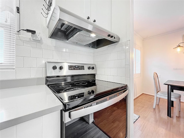 kitchen with light hardwood / wood-style floors, electric stove, tasteful backsplash, white cabinets, and ornamental molding