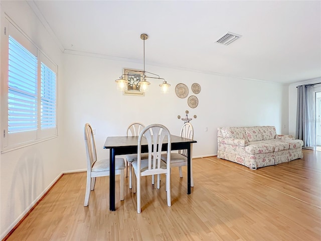 dining area featuring a notable chandelier, light hardwood / wood-style flooring, and crown molding