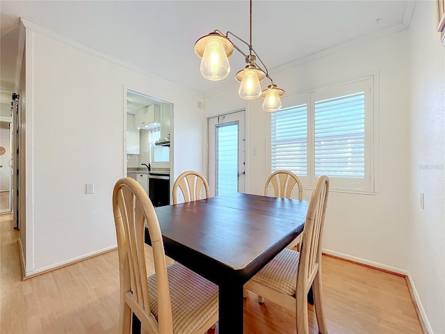 dining space with ornamental molding and light hardwood / wood-style flooring