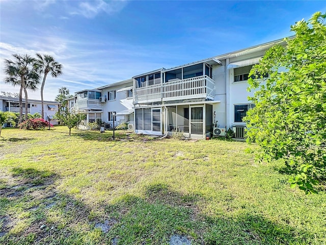 rear view of property featuring a balcony and a lawn