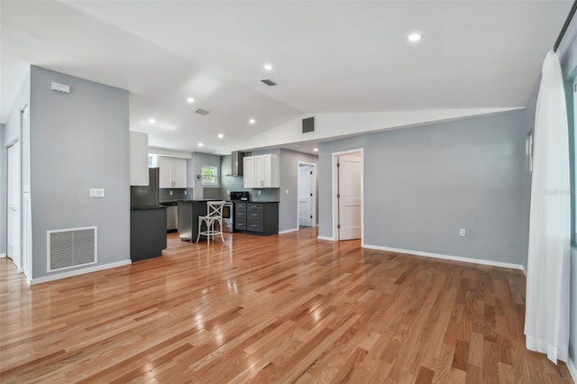 unfurnished living room featuring lofted ceiling and light wood-type flooring