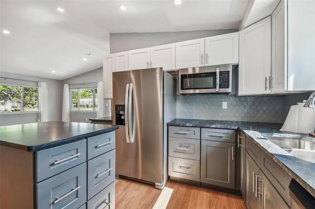 kitchen with appliances with stainless steel finishes, tasteful backsplash, white cabinetry, and lofted ceiling