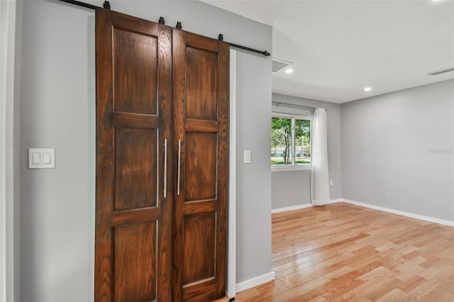 interior space with a barn door and hardwood / wood-style flooring