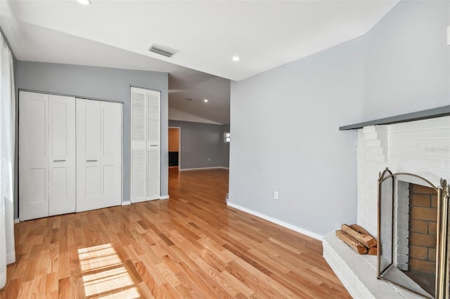 unfurnished living room featuring light hardwood / wood-style floors, a fireplace, and vaulted ceiling