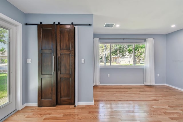 interior space featuring a barn door, light hardwood / wood-style floors, and dark brown cabinetry