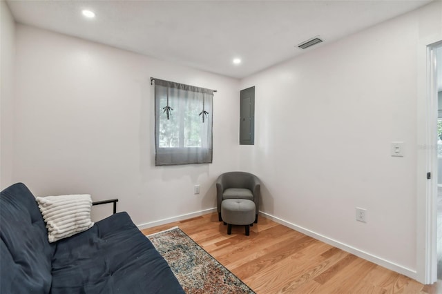 living area with electric panel and hardwood / wood-style floors