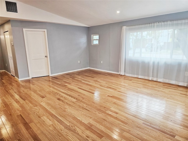 spare room with light hardwood / wood-style floors and lofted ceiling