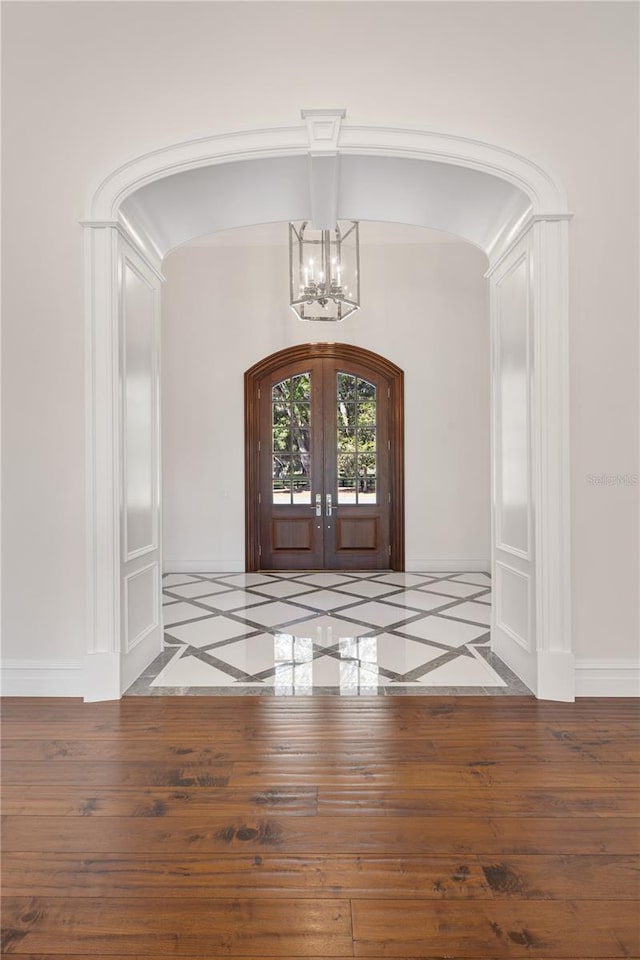 foyer entrance featuring hardwood / wood-style floors, a notable chandelier, and french doors