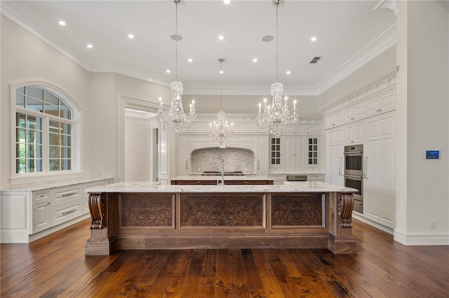 kitchen with light stone counters, a large island with sink, and dark wood-type flooring