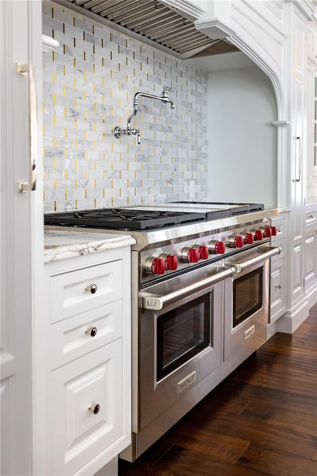 kitchen with white cabinets, backsplash, range with two ovens, dark hardwood / wood-style flooring, and light stone countertops