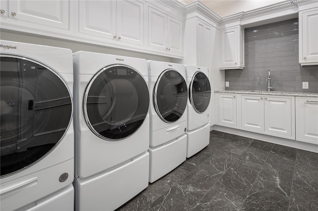 laundry area with cabinets, dark tile flooring, sink, and washing machine and clothes dryer