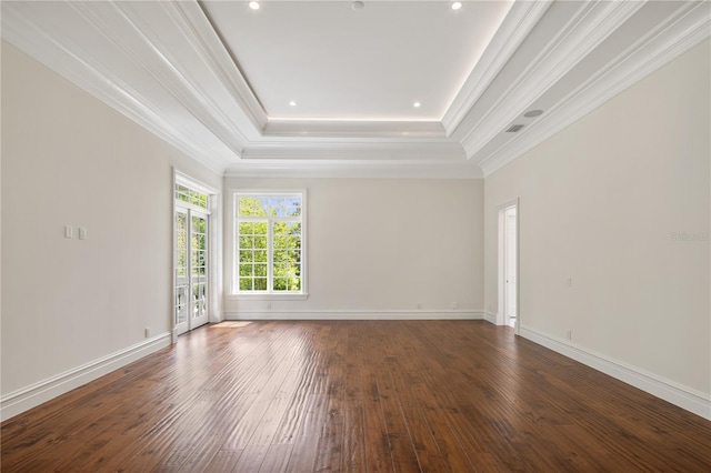 empty room with dark hardwood / wood-style flooring, crown molding, and a tray ceiling