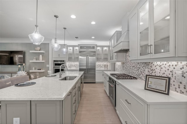 kitchen with pendant lighting, stainless steel appliances, sink, and an island with sink