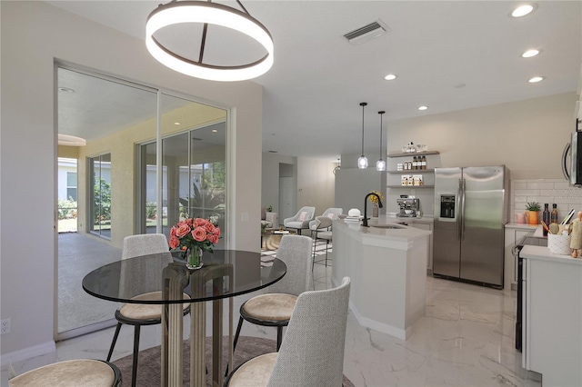 dining space featuring sink and light tile floors