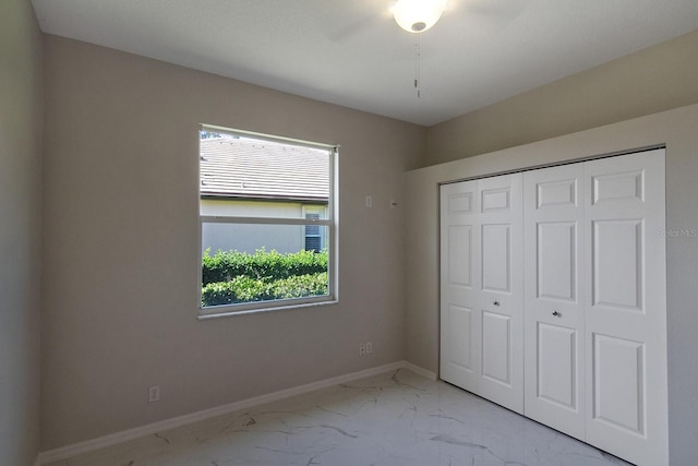 unfurnished bedroom with a closet, multiple windows, ceiling fan, and tile floors