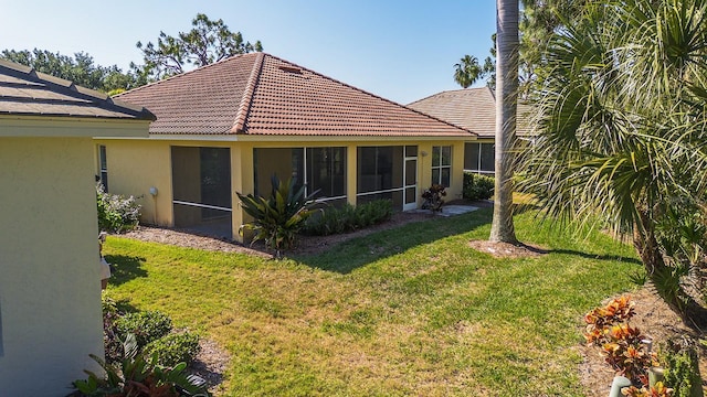 rear view of property with a sunroom and a lawn