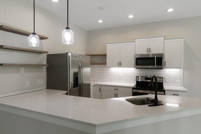 kitchen featuring appliances with stainless steel finishes, white cabinets, backsplash, hanging light fixtures, and kitchen peninsula