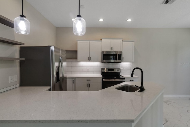 kitchen featuring appliances with stainless steel finishes, white cabinets, sink, tasteful backsplash, and pendant lighting