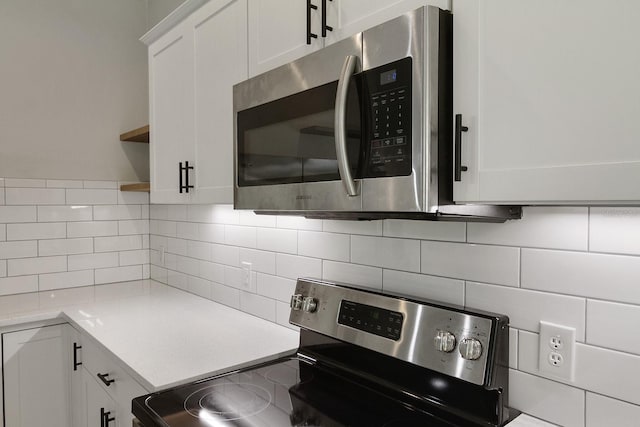 kitchen with backsplash, stainless steel appliances, and white cabinets