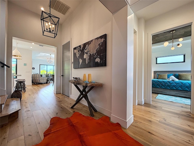 hall with wood-type flooring, a towering ceiling, and an inviting chandelier