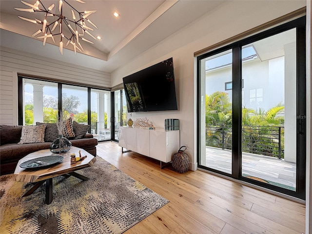 living room with an inviting chandelier, light hardwood / wood-style flooring, and a raised ceiling