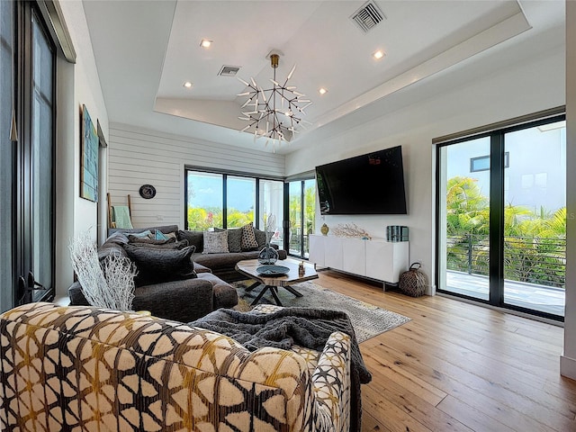 living room with a raised ceiling, an inviting chandelier, and hardwood / wood-style flooring