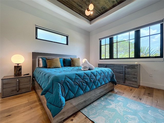 bedroom with light hardwood / wood-style flooring and a raised ceiling