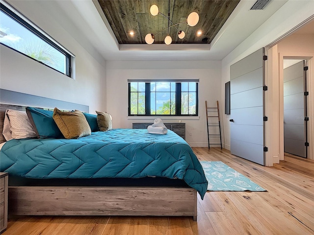 bedroom featuring wooden ceiling, light hardwood / wood-style floors, and a raised ceiling