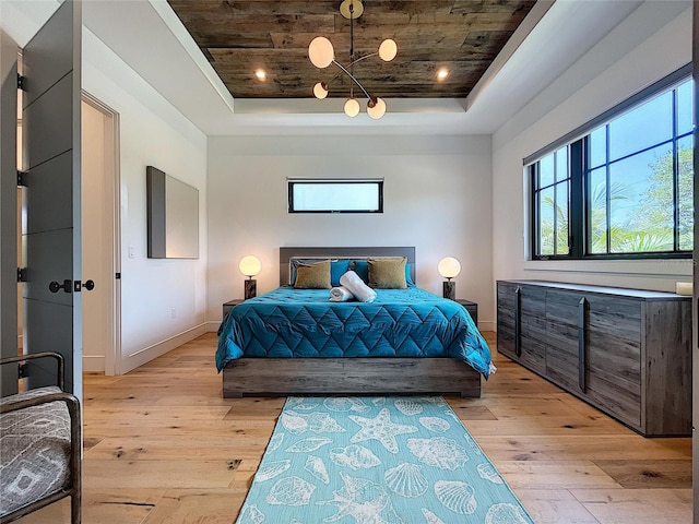 bedroom with wooden ceiling, light hardwood / wood-style flooring, and a tray ceiling