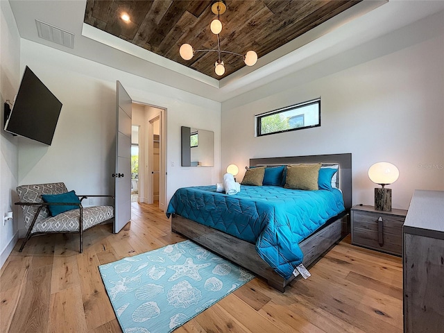 bedroom with a tray ceiling, wooden ceiling, and light wood-type flooring