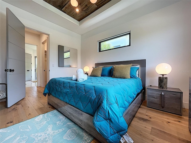 bedroom with wooden ceiling, hardwood / wood-style floors, ceiling fan, and a tray ceiling