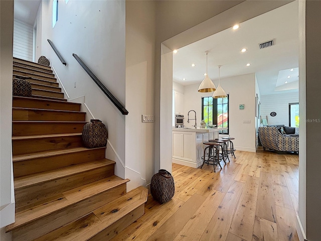 stairs featuring light hardwood / wood-style flooring and sink