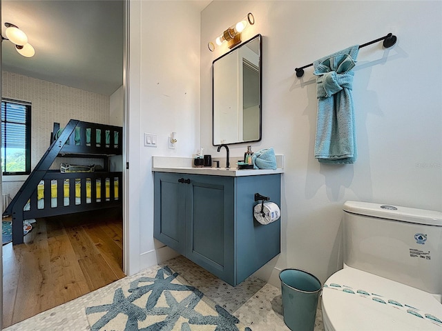 bathroom featuring hardwood / wood-style floors, vanity with extensive cabinet space, and toilet