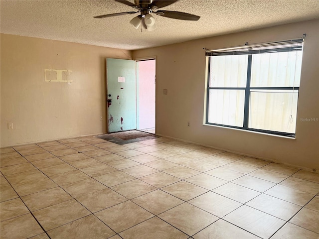 tiled empty room with ceiling fan and a textured ceiling