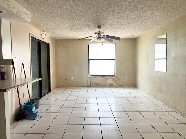 tiled spare room with ceiling fan and a textured ceiling