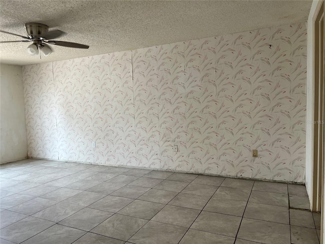 unfurnished room with tile flooring, ceiling fan, and a textured ceiling