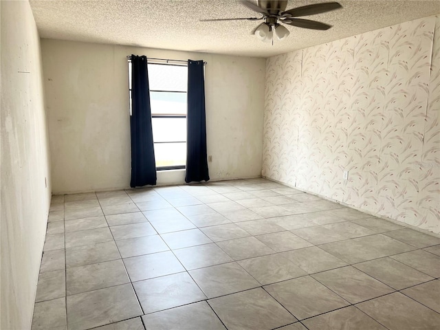 tiled empty room featuring ceiling fan and a textured ceiling