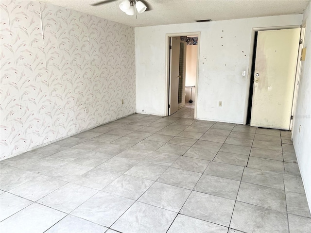 spare room featuring ceiling fan, a textured ceiling, and light tile flooring