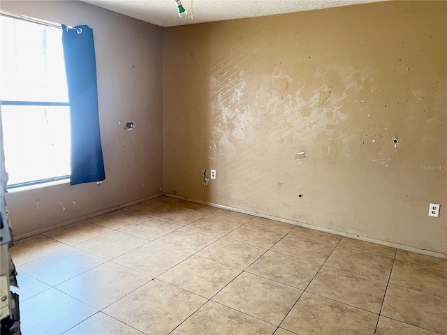 tiled empty room with a textured ceiling