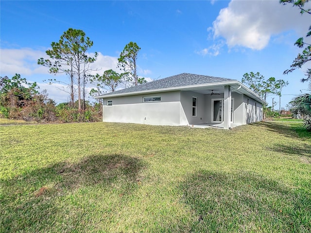 back of property with a yard and ceiling fan