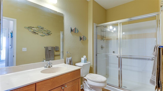 bathroom with vanity, a shower with shower door, and toilet