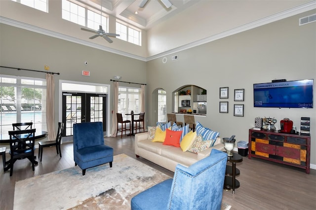 living room featuring hardwood / wood-style floors, ceiling fan, a healthy amount of sunlight, and a towering ceiling