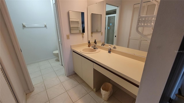 bathroom with vanity, toilet, a shower with shower door, and tile patterned flooring