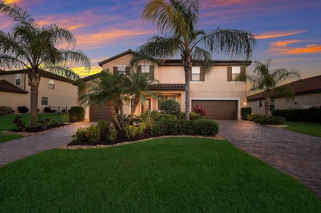 mediterranean / spanish-style home featuring a garage and a lawn